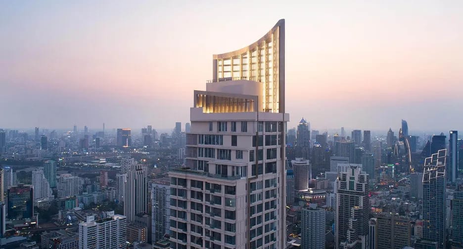 The Esse Asoke tower and illuminated crown above the Bangkok skyline at sunset