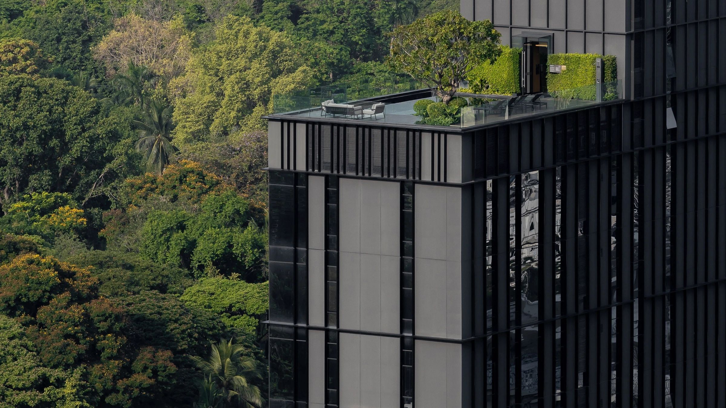 Sindhorn Lumpini facade and landscaped terrace beside park trees