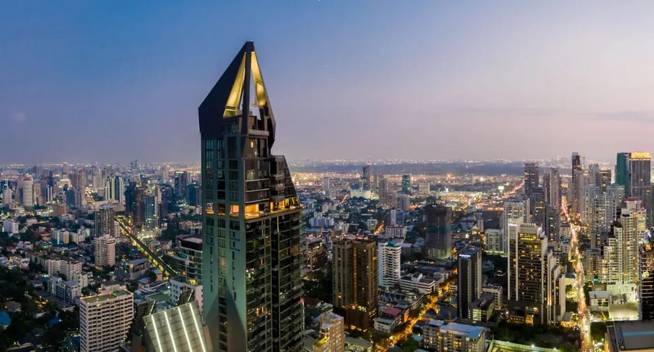 MARQUE Sukhumvit tower with an illuminated crown above the Bangkok skyline at dusk